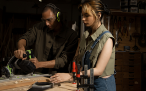 two people working on wood with a power saw